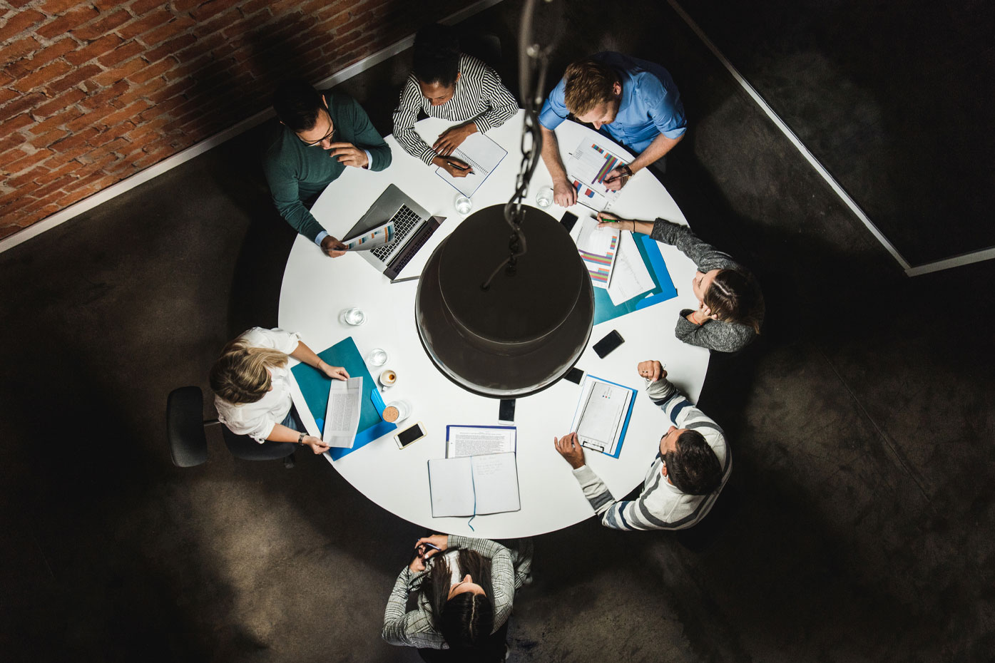 Above view of business colleagues analysing reports on a meeting at the table