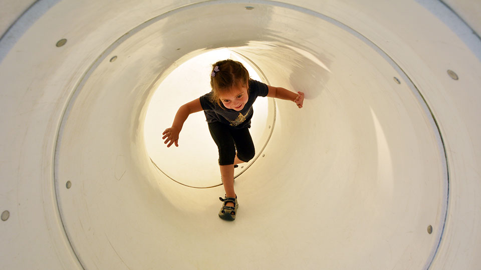 Child plays in playground tunnel