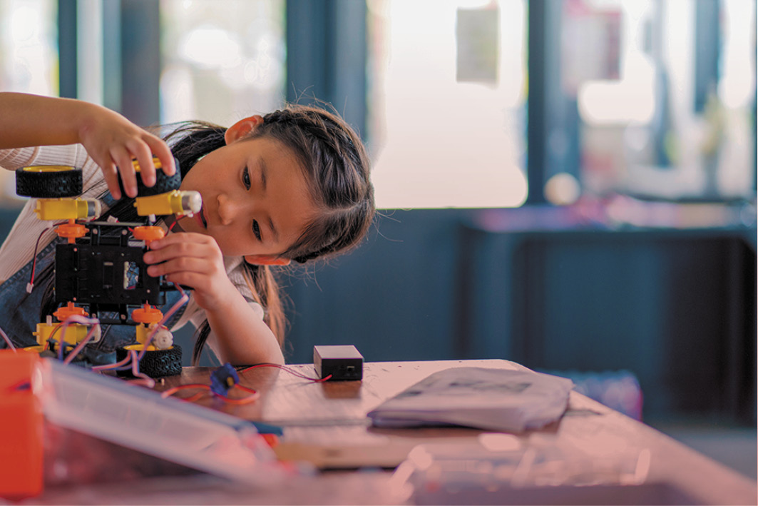 Image of a young girl in a classroom assembling an educational construction toy