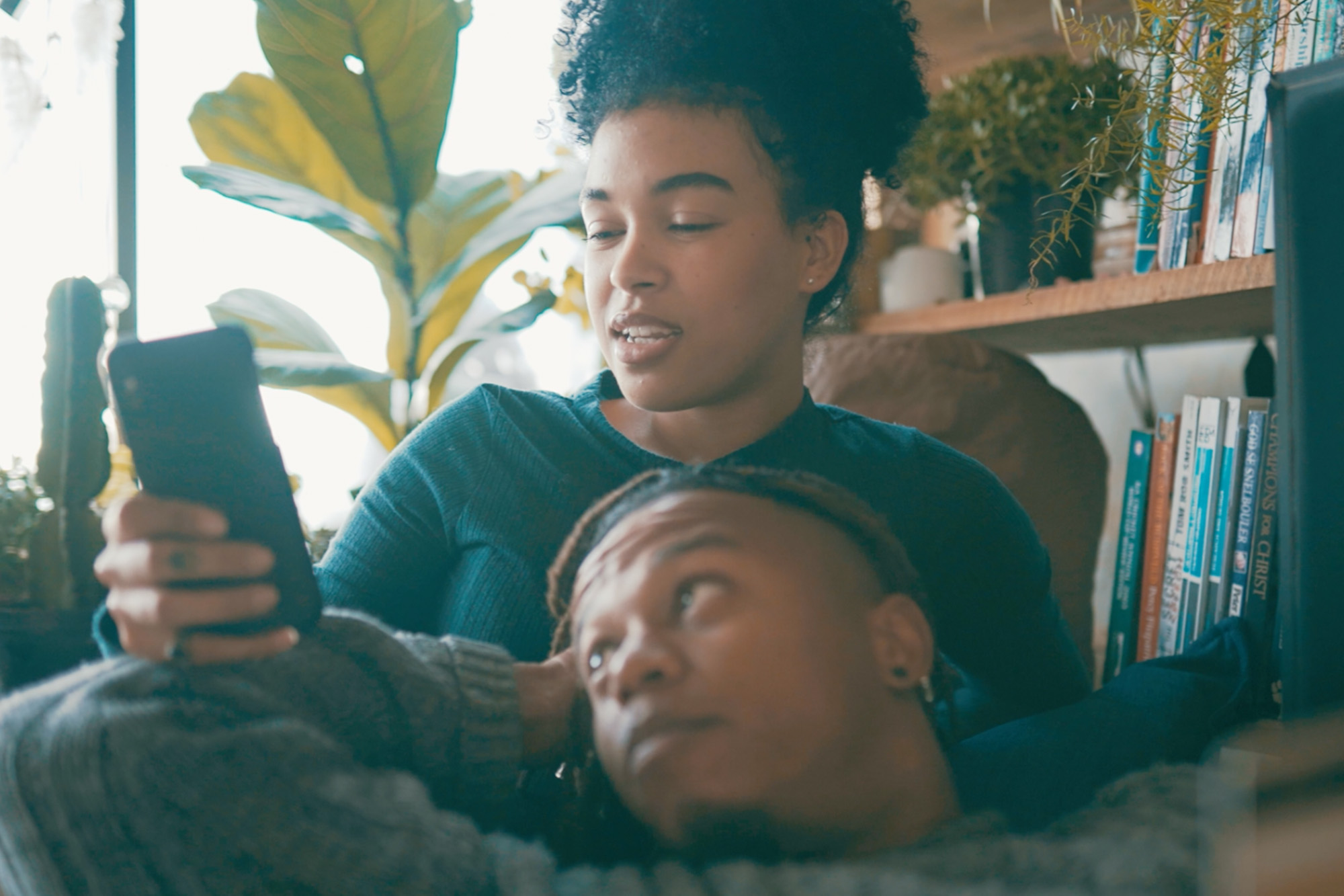 Couple relaxing indoors, viewing something on a mobile phone