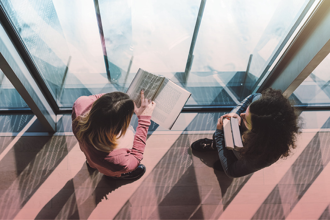 Students in a hallway window discussing a book