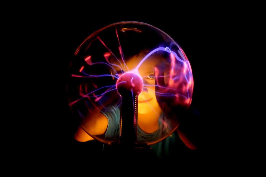 Child with hands on a plasma ball
