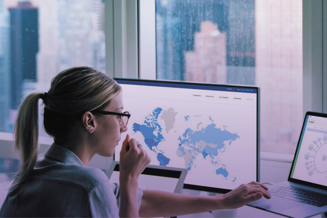 Woman with glasses sitting at a desk working on a laptop